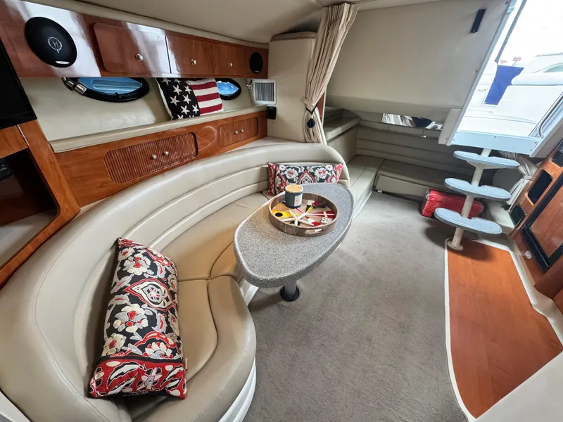 Slide: The Image of 2005 Larson 370 CABRIO interior with curved seating, decorative pillows, and a central table. - 15