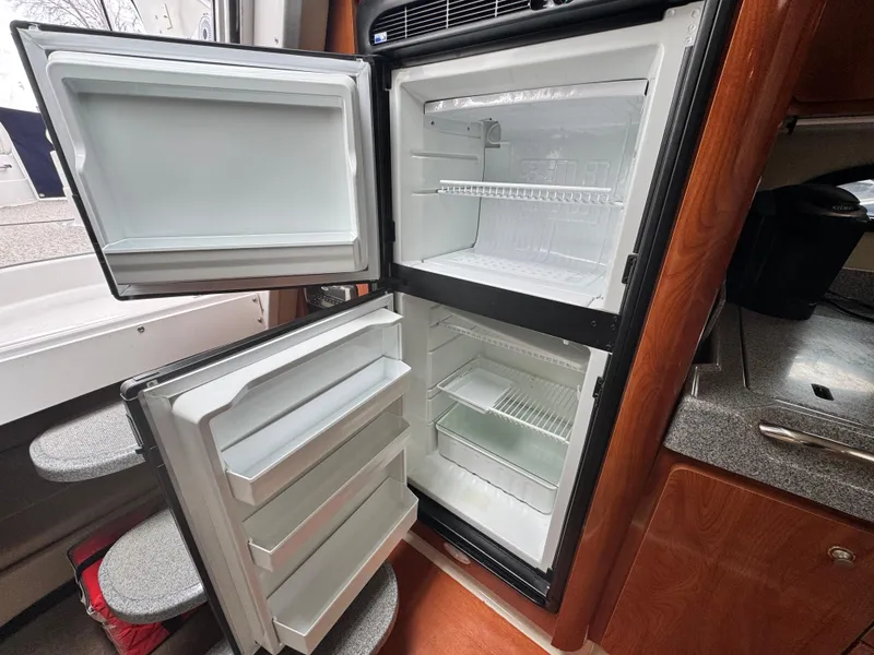 Slide: The Image of Open refrigerator inside 2005 Larson 370 CABRIO boat, showcasing storage compartments. - 19