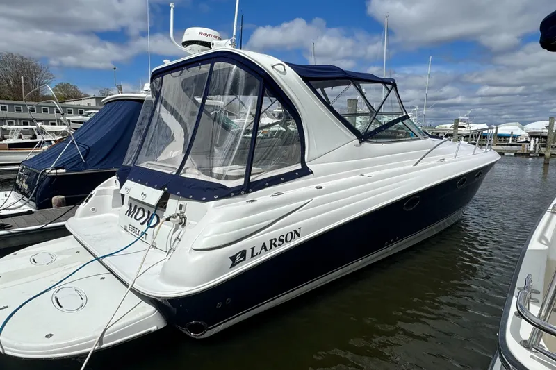Slide: The Image of 2005 Larson 370 Cabrio boat docked in a marina under a cloudy sky. - 2
