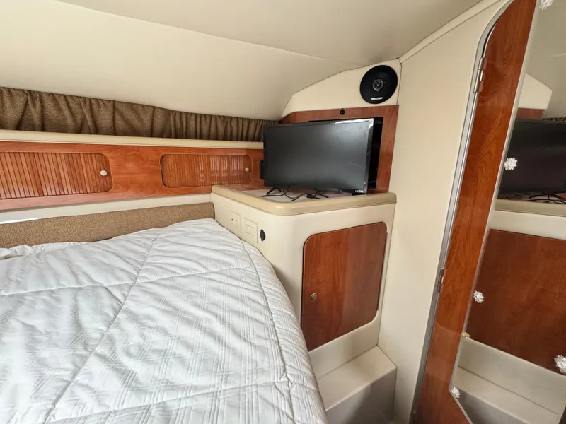 Slide: The Image of 2005 Larson 370 Cabrio cabin interior with bed, TV, and wooden cabinetry. - 23