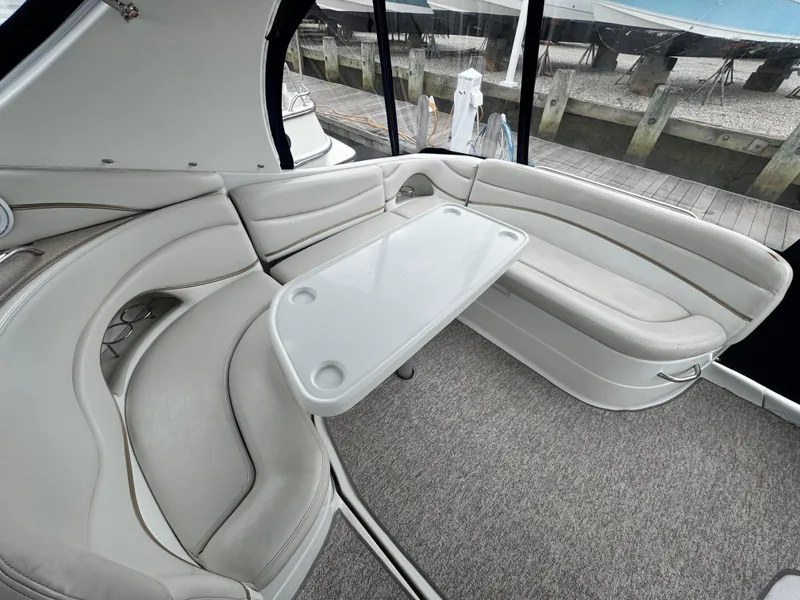 Slide: The Image of 2005 Larson 370 Cabrio boat interior with plush seating and table, dockside view. - 7