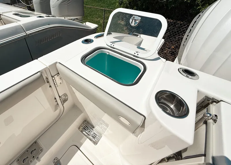 Slide: The Image of 2025 Pursuit DC 326 Dual Console boat with open storage compartment and cup holders. - 10