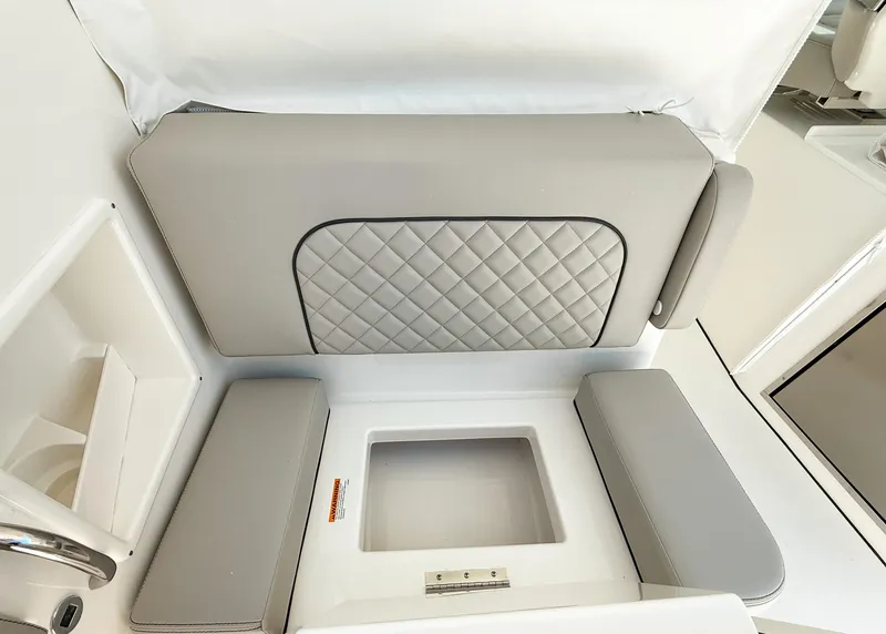 Slide: The Image of 2025 Pursuit DC 326 Dual Console interior seating with quilted upholstery and storage compartment. - 12