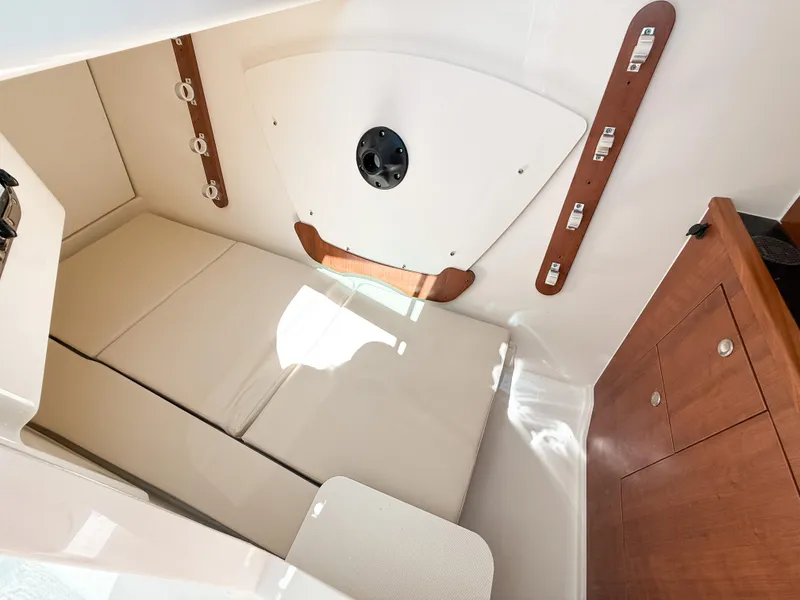 Slide: The Image of 2025 Pursuit DC 326 Dual Console cabin interior with cushioned seating and wooden accents. - 21