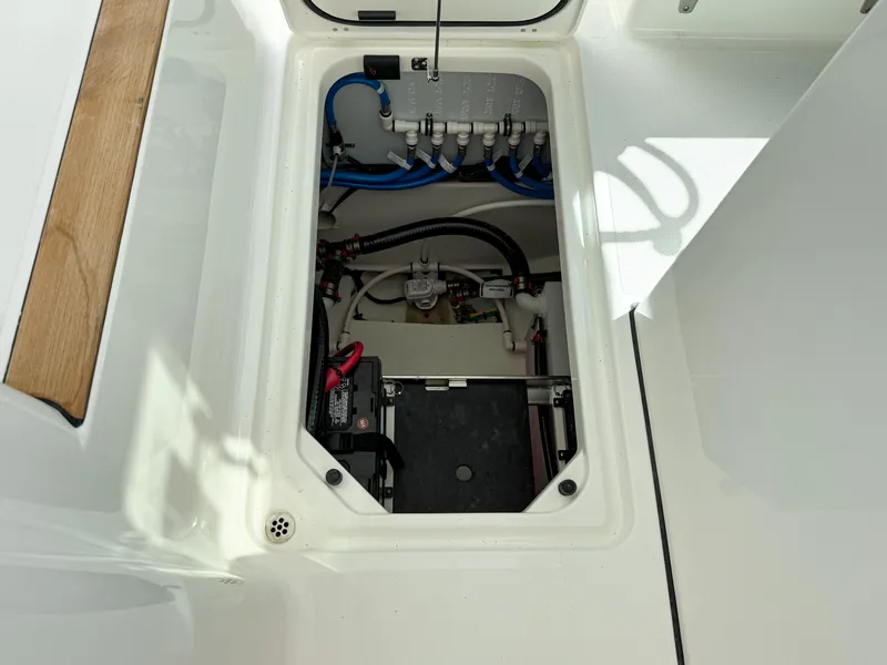 Slide: The Image of 2025 Pursuit DC 326 Dual Console boat storage compartment with visible wiring and components. - 31