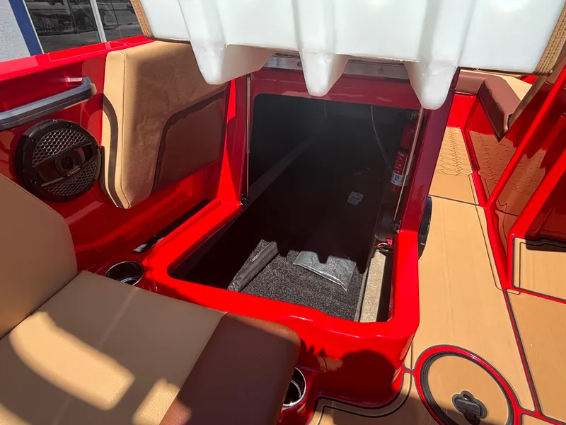 Slide: The Image of 2025 MasterCraft NXT24 boat interior with open storage compartment, red and tan seating. - 10