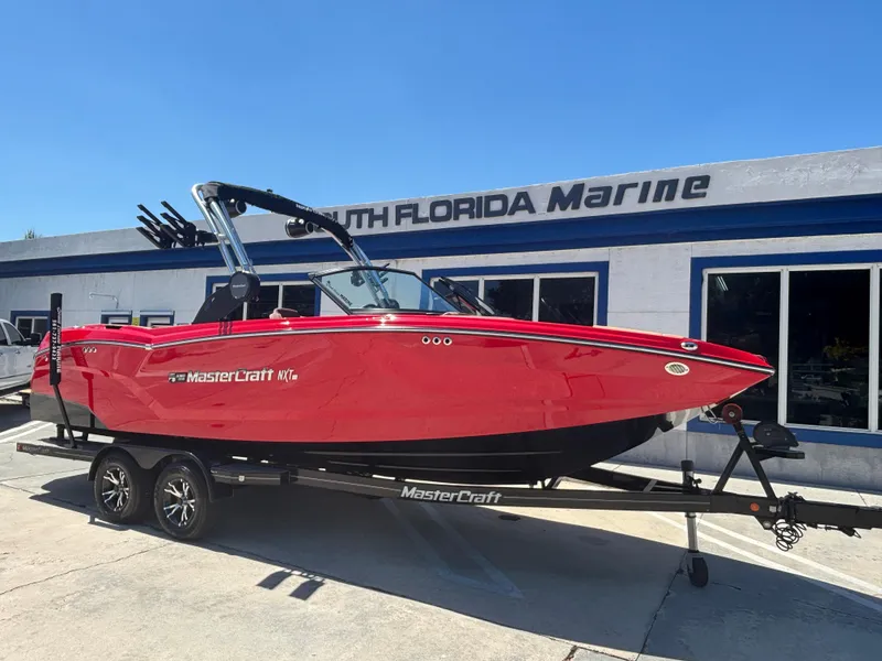 Slide: The Image of 2025 MasterCraft NXT24 boat in vibrant red on a trailer at South Florida Marine. - 2