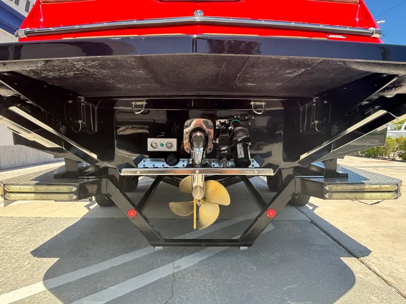 Slide: The Image of 2025 MasterCraft NXT24 boat stern view with propeller and rudder, parked on concrete. - 4