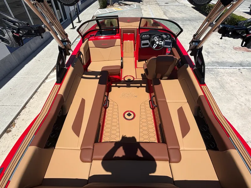 Slide: The Image of 2025 MasterCraft NXT24 boat interior with tan and red seating, modern dashboard, and spacious layout. - 6