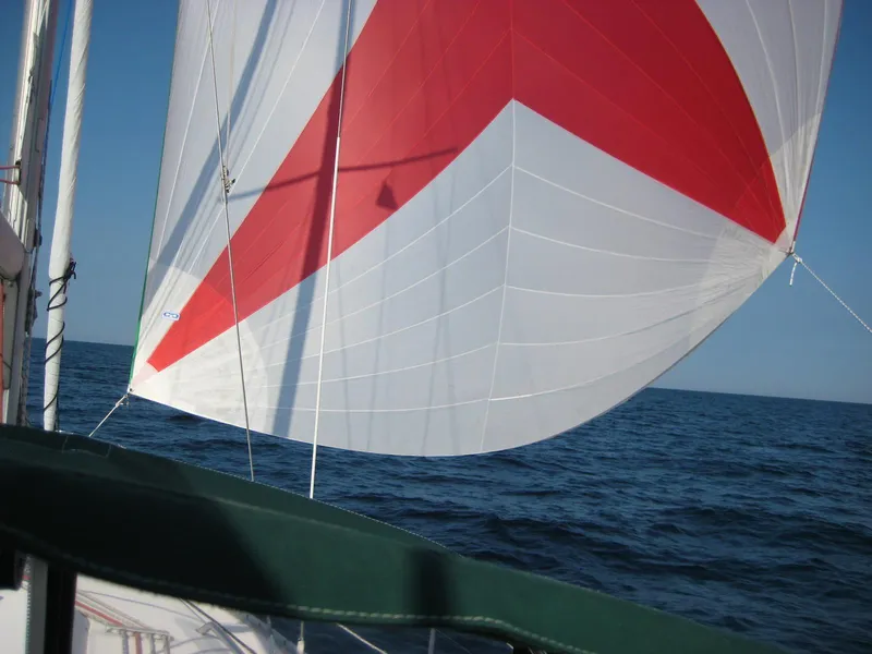 Slide: The Image of Sailing on a 2002 Beneteau 331 with a red and white spinnaker over open sea. - 12