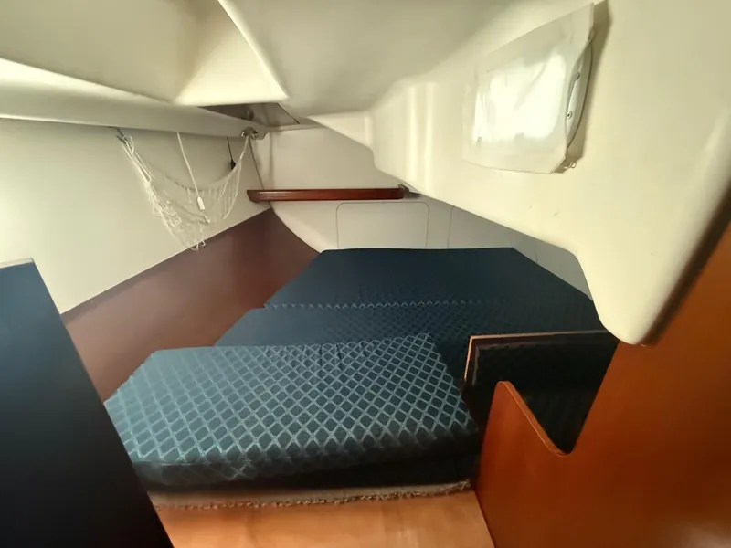 Slide: The Image of 2002 Beneteau 331 yacht cabin with blue mattress and wooden accents. - 41