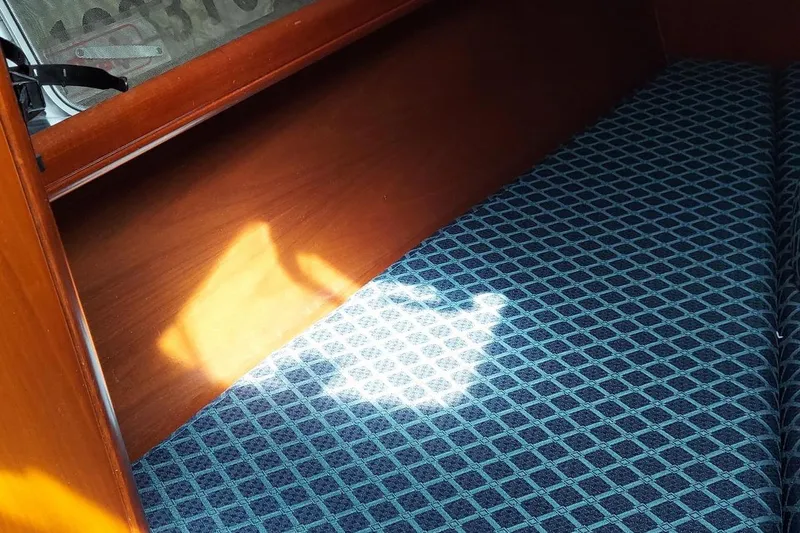 Slide: The Image of Interior of 2002 Beneteau 331 sailboat with patterned blue upholstery and wooden shelving. - 44