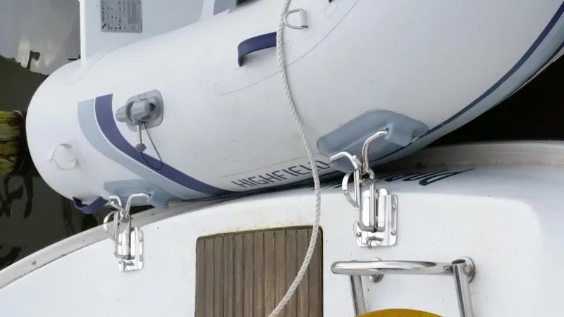 Slide: The Image of Inflatable boat secured to a 2002 Beneteau 331 sailboat with metal hooks and rope. - 68