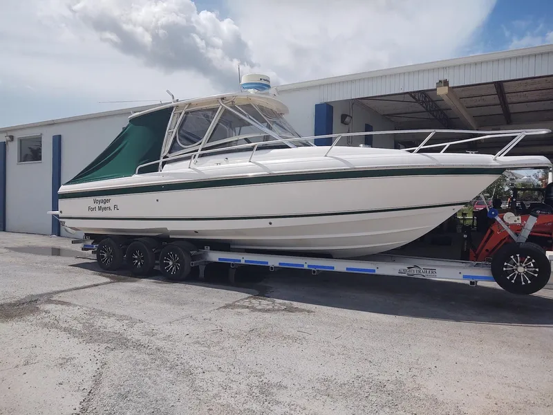 The Image of 2005 Intrepid 310 Walkaround boat on trailer, parked outside a building. - 0