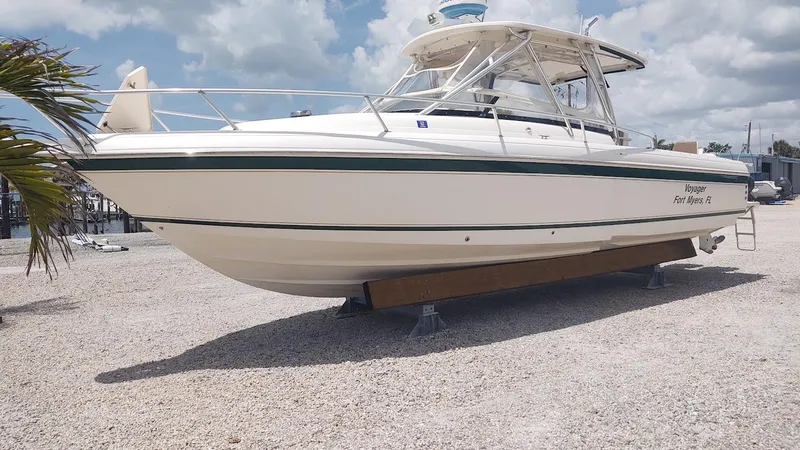 Slide: The Image of 2005 Intrepid 310 Walkaround boat on gravel, under a cloudy sky. - 1