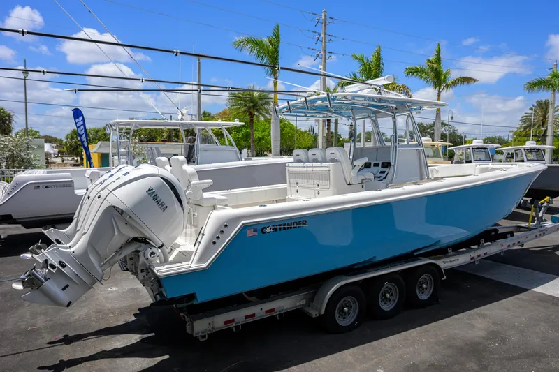 Slide: The Image of 2022 Contender 35 ST boat on trailer, blue hull, Yamaha engines, palm trees in background. - 12