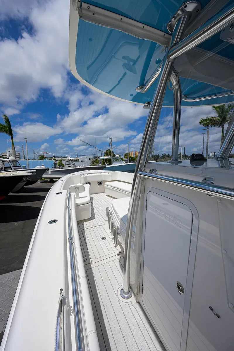 Slide: The Image of 2022 Contender 35 ST boat with sleek design, blue canopy, and spacious deck under a sunny sky. - 13