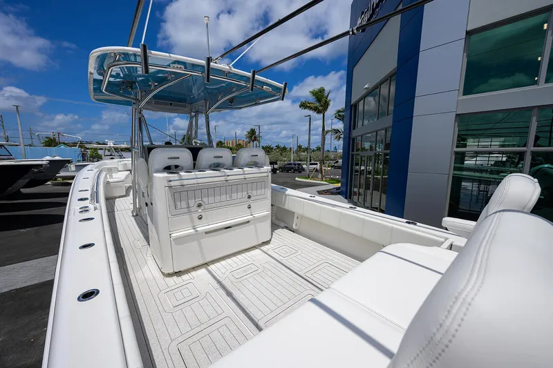 Slide: The Image of 2022 Contender 35 ST boat with white seating and sleek design, docked near a modern building. - 39