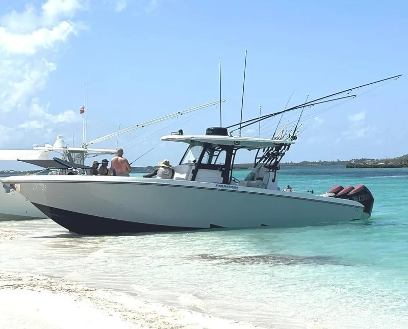 Slide: The Image of 2024 Fountain 34 TE boat anchored on a sandy beach with people onboard. - 0