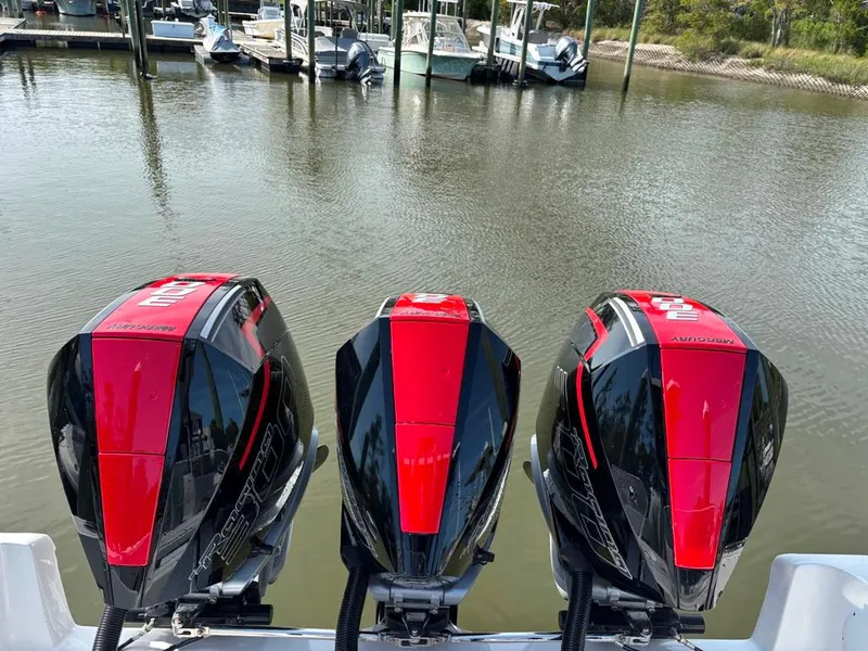 Slide: The Image of Triple outboard motors on a 2024 Fountain 34 TE boat, docked by the water. - 4