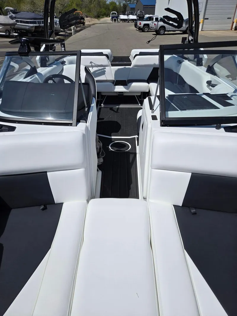 Slide: The Image of 2025 Moomba Craz boat interior with white and black seating, open windshield, and cup holder. - 5