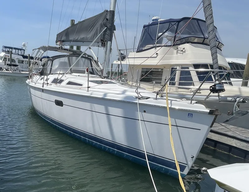 Slide: The Image of 2004 Hunter 36 sailboat docked in marina, featuring sleek white hull and black sail cover. - 0
