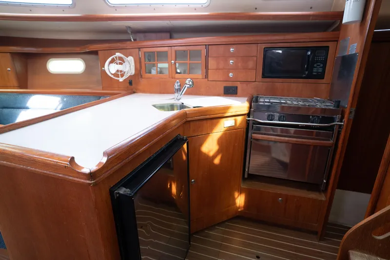 Slide: The Image of 2004 Hunter 36 yacht kitchen with wood cabinetry, stove, microwave, and sink. - 22