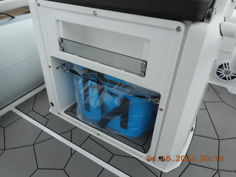 Slide: The Image of 2025 Highfield Sport 560 boat storage compartment with blue bag on hexagonal-patterned deck. - 22