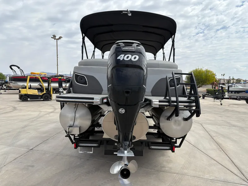 Slide: The Image of 2021 Bennington 25 LFBC pontoon boat with powerful 400 HP engine, parked outdoors. - 2