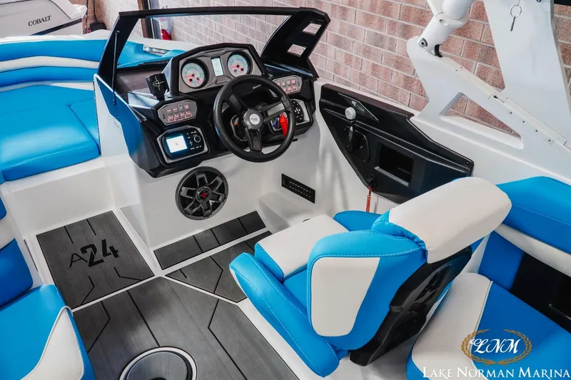Slide: The Image of 2019 Axis A24 boat interior with blue and white seating, modern dashboard, and steering wheel. - 12