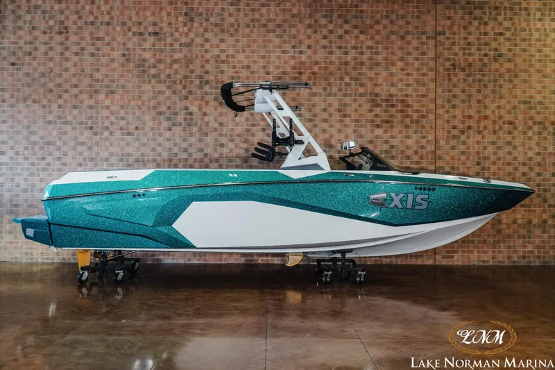 Slide: The Image of 2024 Axis A245 boat with teal and white design, displayed indoors at Lake Norman Marina. - 1