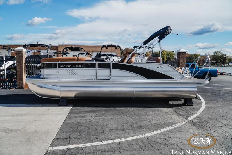 Slide: The Image of 2025 Bennington 22MSB pontoon boat at Lake Norman Marina, under a clear blue sky. - 1