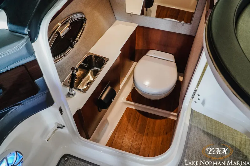 Slide: The Image of 2018 Chaparral 267 SSX boat interior with compact bathroom, sink, and wooden flooring. - 17