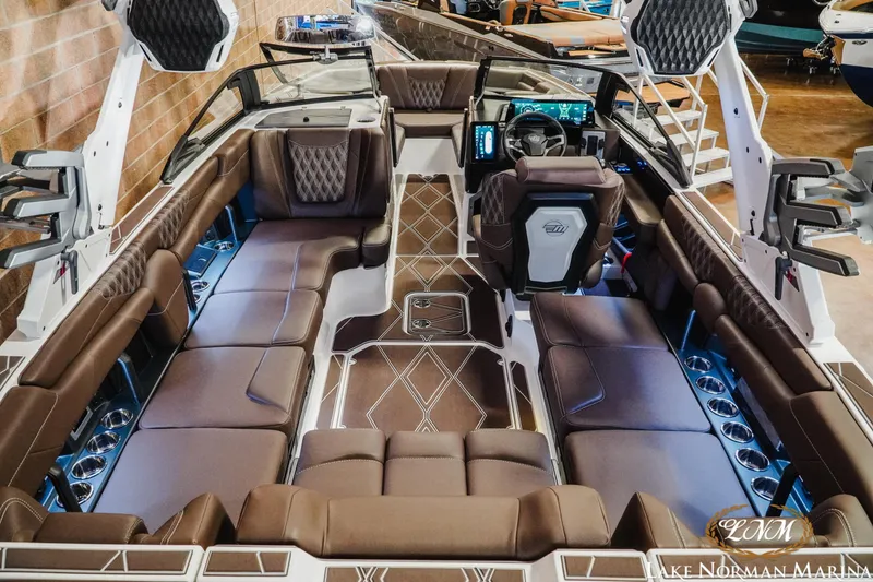 Slide: The Image of Luxurious interior of 2025 Malibu M230 boat with brown leather seating and modern dashboard. - 14