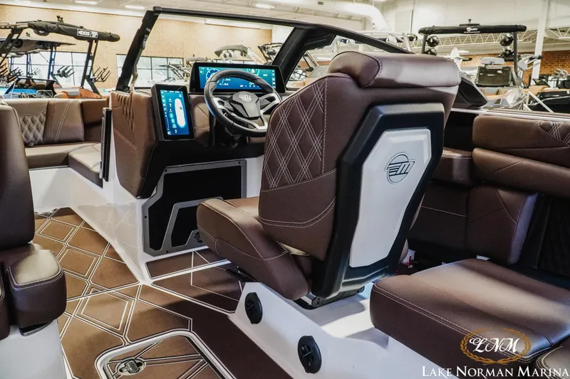 Slide: The Image of 2025 Malibu M230 boat interior with luxurious brown seating and modern dashboard at Lake Norman Marina. - 19