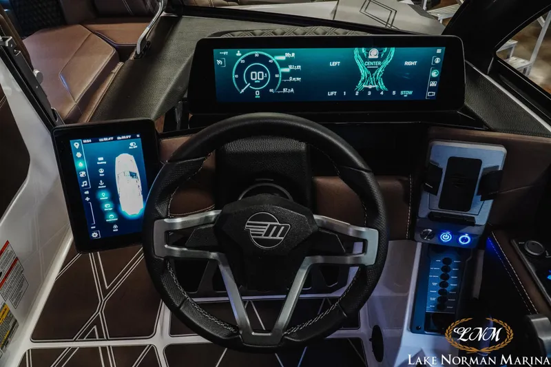Slide: The Image of 2025 Malibu M230 boat dashboard with advanced digital displays and steering wheel at Lake Norman Marina. - 23