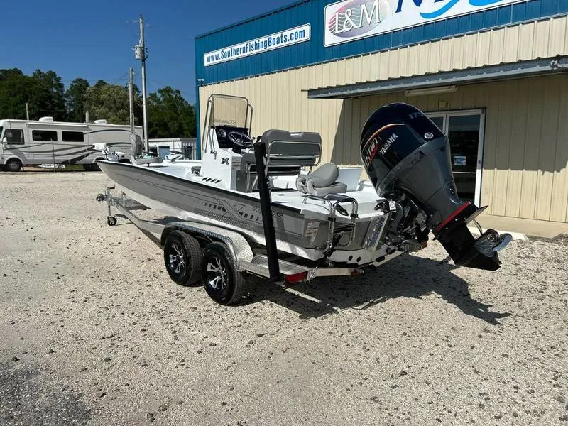 Slide: The Image of 2025 Xpress H22B boat on trailer outside dealership, featuring powerful outboard motor. - 2