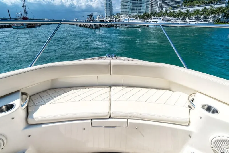 Slide: The Image of 2018 Chris-Craft Launch boat with white seating, docked in a marina with cityscape background. - 8