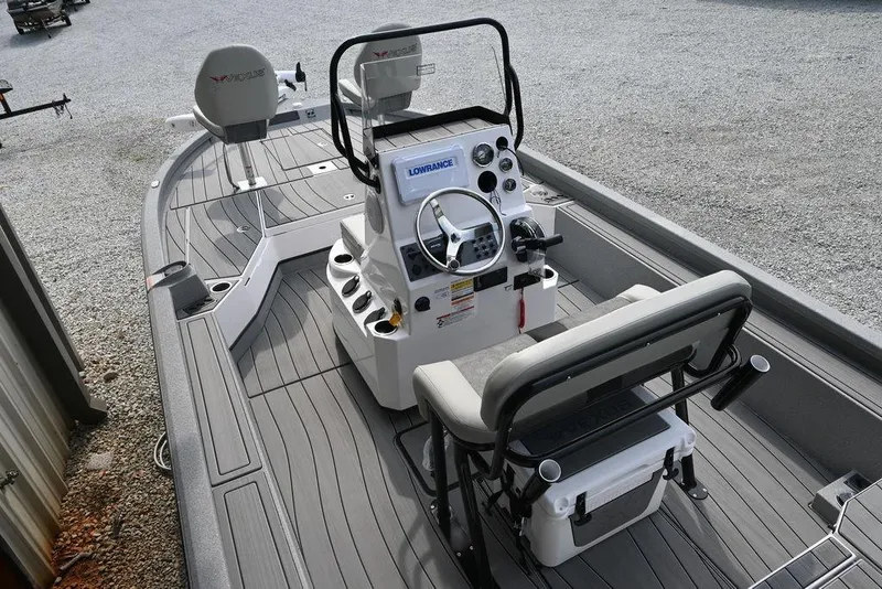 Slide: The Image of 2025 Vexus ACX2210 boat interior with steering console and seating on a gravel surface. - 2