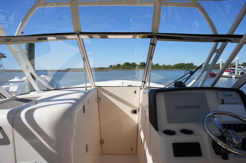 Slide: The Image of 2022 Grady-White Freedom 285 boat cockpit with Garmin navigation, overlooking serene waters. - 23