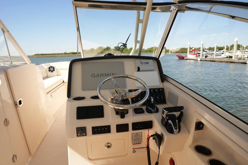 Slide: The Image of 2022 Grady-White Freedom 285 boat dashboard with Garmin navigation, docked by the water. - 26