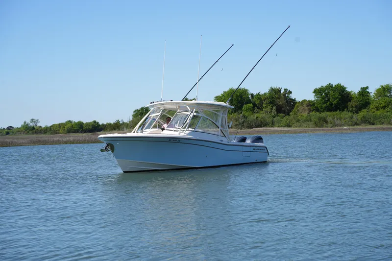 Slide: The Image of 2022 Grady-White Freedom 285 boat on calm water, clear sky, lush greenery in background. - 3