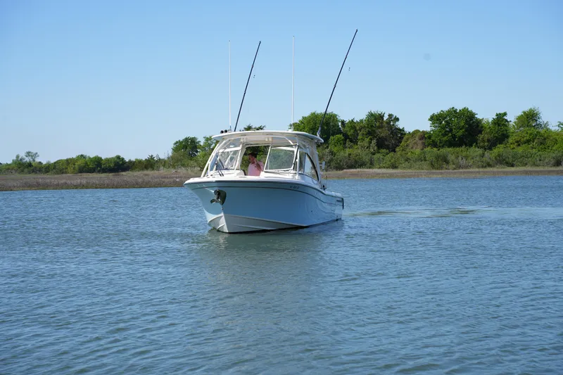 Slide: The Image of 2022 Grady-White Freedom 285 boat cruising on calm water with trees in the background. - 4