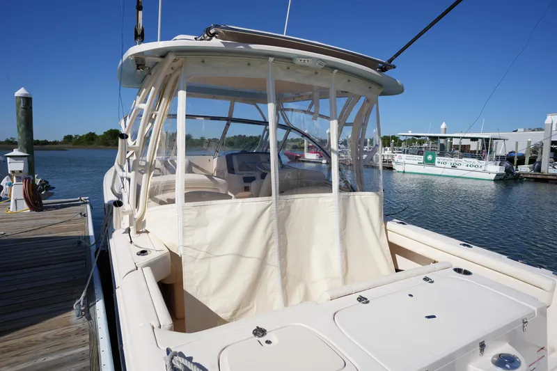 Slide: The Image of 2022 Grady-White Freedom 285 boat docked, featuring a covered cockpit and clear skies. - 47
