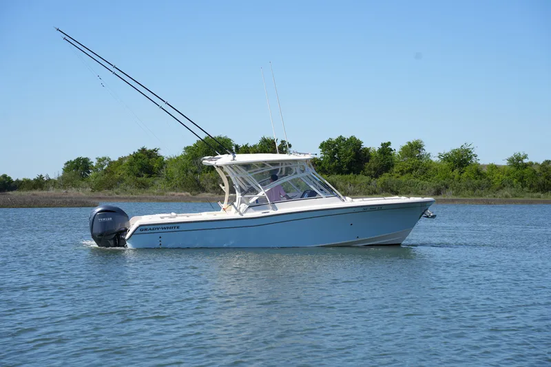 Slide: The Image of 2022 Grady-White Freedom 285 boat cruising on calm water with trees in the background. - 8