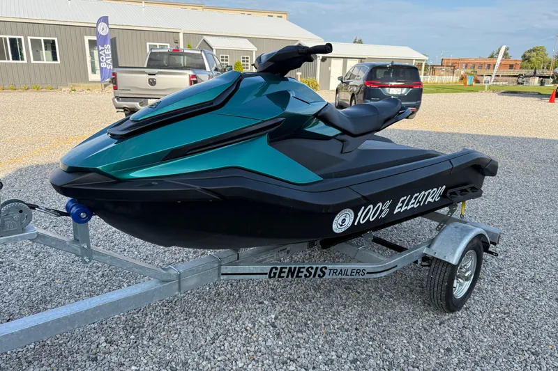 Slide: The Image of 2024 Taiga Orca electric jet ski on Genesis trailer, parked on gravel. - 7