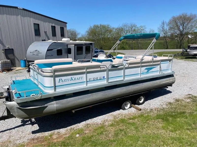 Slide: The Image of 2023 Parti Kraft 240 SC pontoon boat on trailer, parked outdoors near a building. - 1
