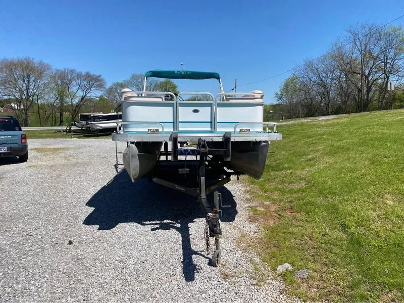 Slide: The Image of 2023 Parti Kraft 240 SC pontoon boat on trailer, parked on gravel near grassy area. - 2
