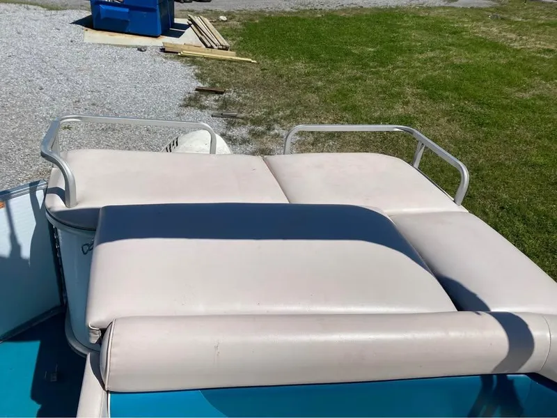 Slide: The Image of 2023 Parti Kraft 240 SC boat with cushioned seating, parked on gravel near grass. - 8