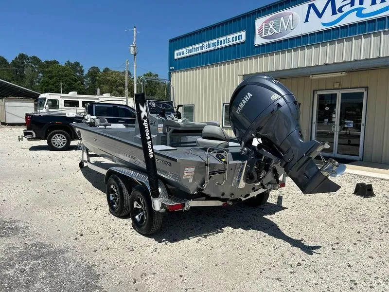 Slide: The Image of 2025 Xpress H210B boat with Yamaha engine parked outside a marine shop. - 4